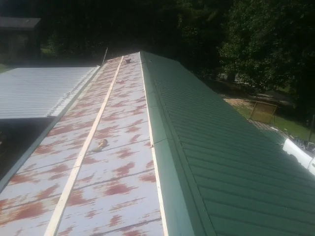 Old rusted panels beside newly installed green metal roofing — Wind Damage Roof Repair by Roofing Brothers in Horse Creek