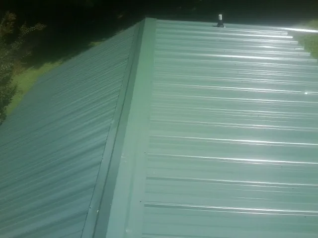 New green metal panels meeting at the ridge of a roof — Flat Roof Repair work by our crew in Horse Creek