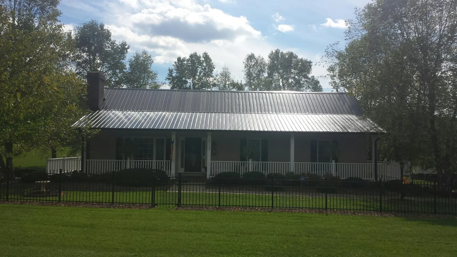 Gray metal roof on a brick ranch with a full width front porch — Gutter Guard Installation work by our crew in Horse Creek