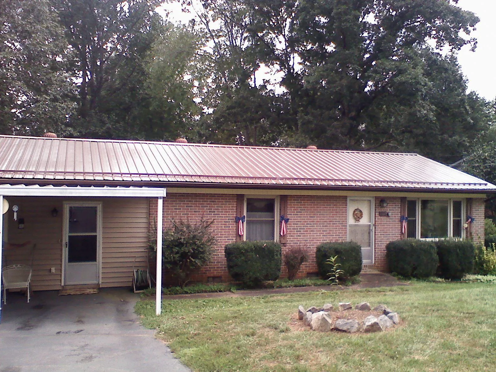 Bronze metal roof and carport on a brick ranch home — Roof Repair work by our crew in Horse Creek