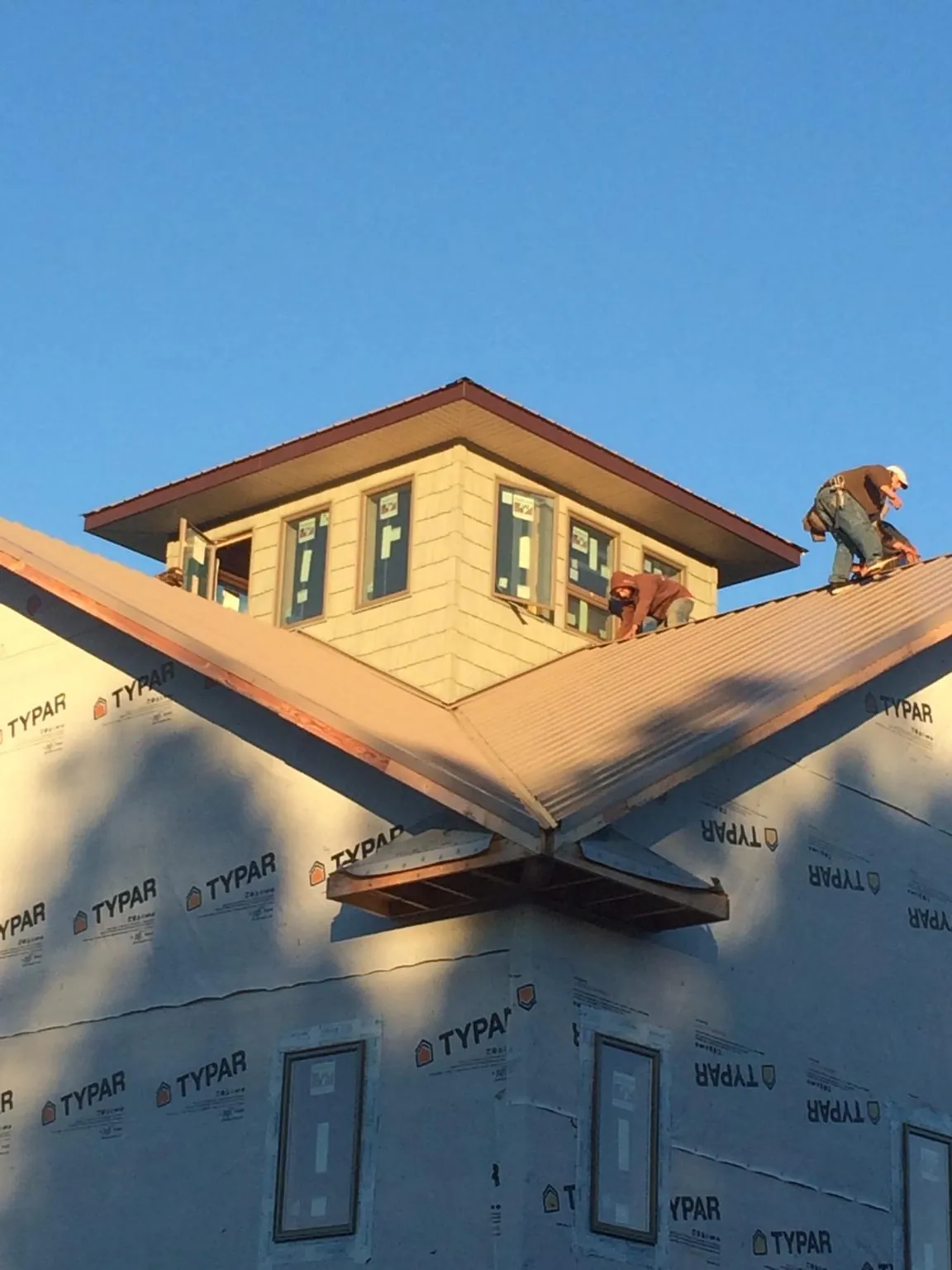 Roofers working around a rooftop cupola on a new metal roof at sunset — Roof Waterproofing in Horse Creek by Roofing Brothers